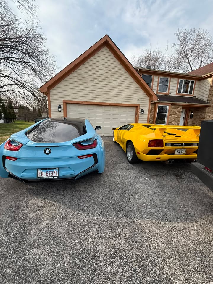 A BMW i8 and a yellow Lamborghini Diablo detailed side by side in a driveway